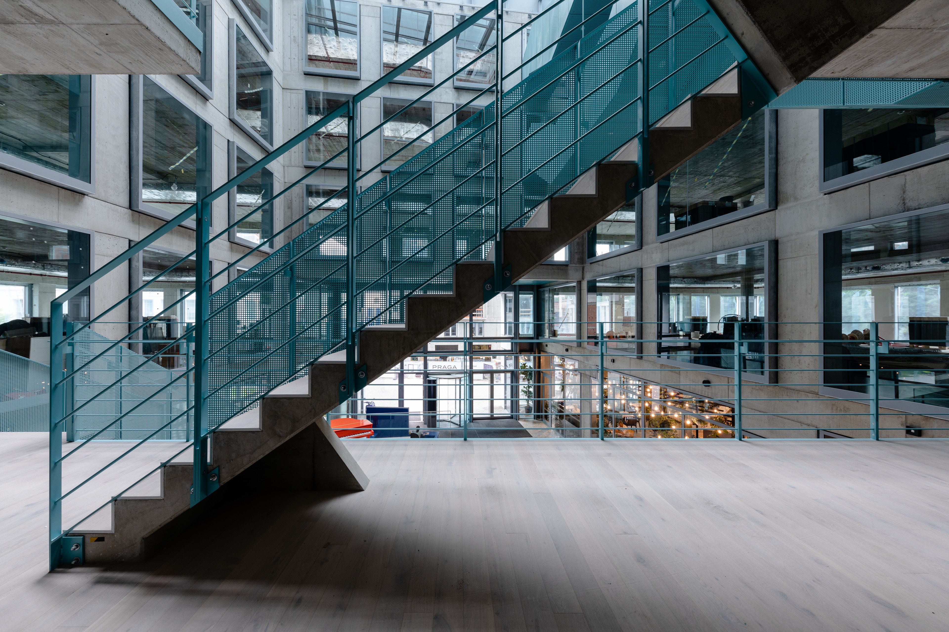 Lobby Five Moderní kancelářská hala s lidmi, kteří sedí a chodí, s červenými židlemi a velkými hodinami.