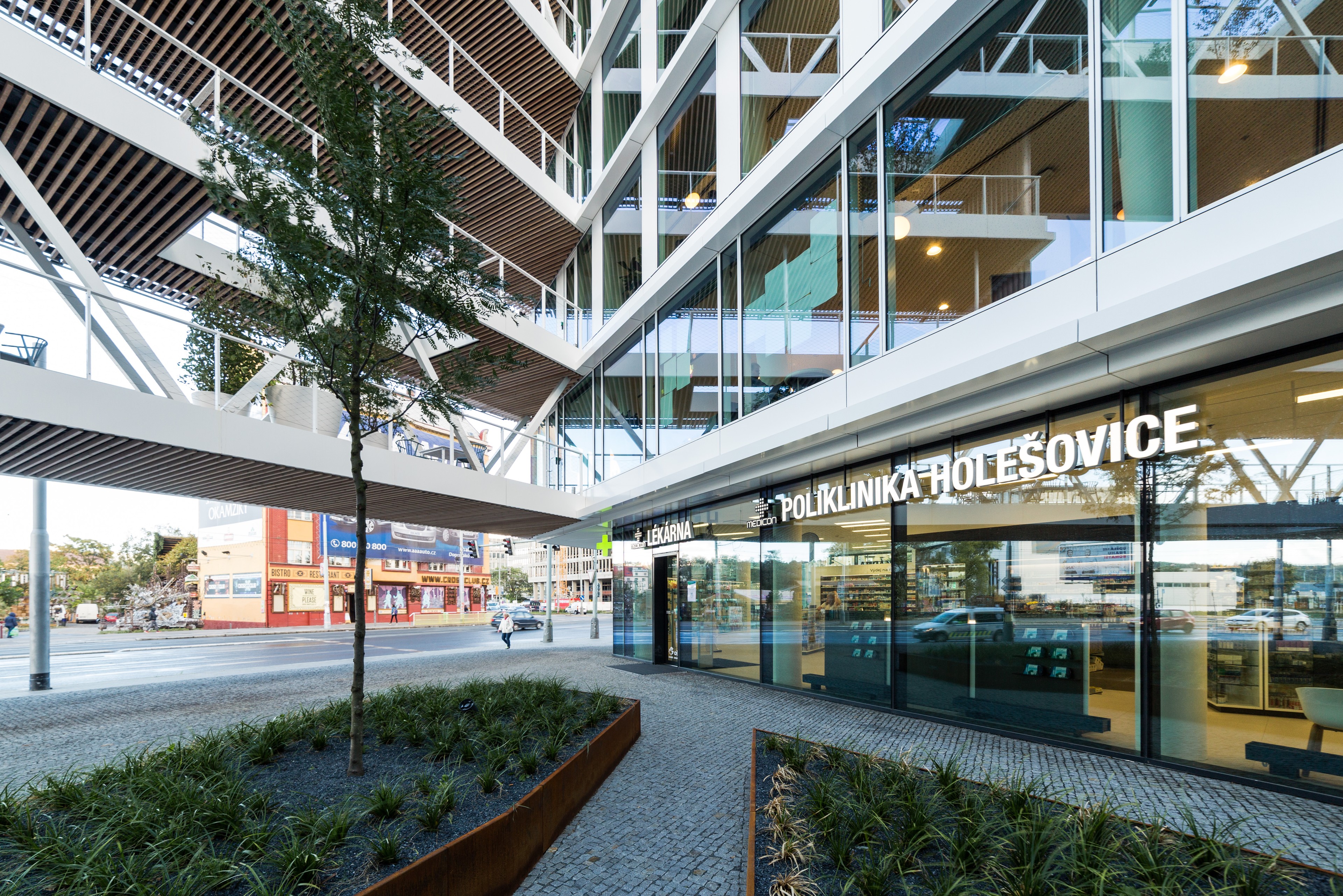 Pharmacy and polyclinic at Visionary Modern medical clinic with a glass facade with outdoor greenery and an urban street.