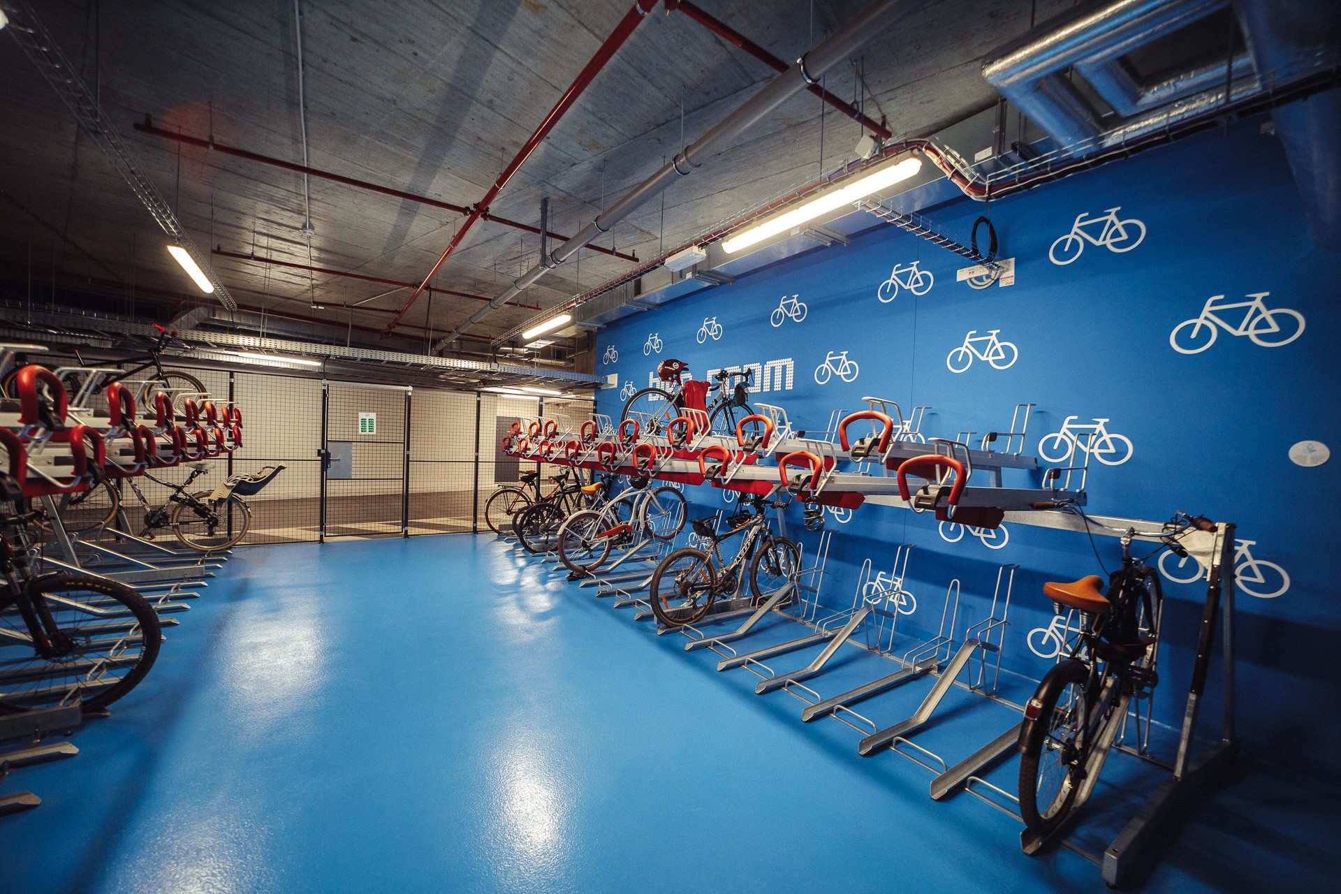 Bicycle parking Indoor parking space for bicycles with a blue floor and bike racks by the blue wall.