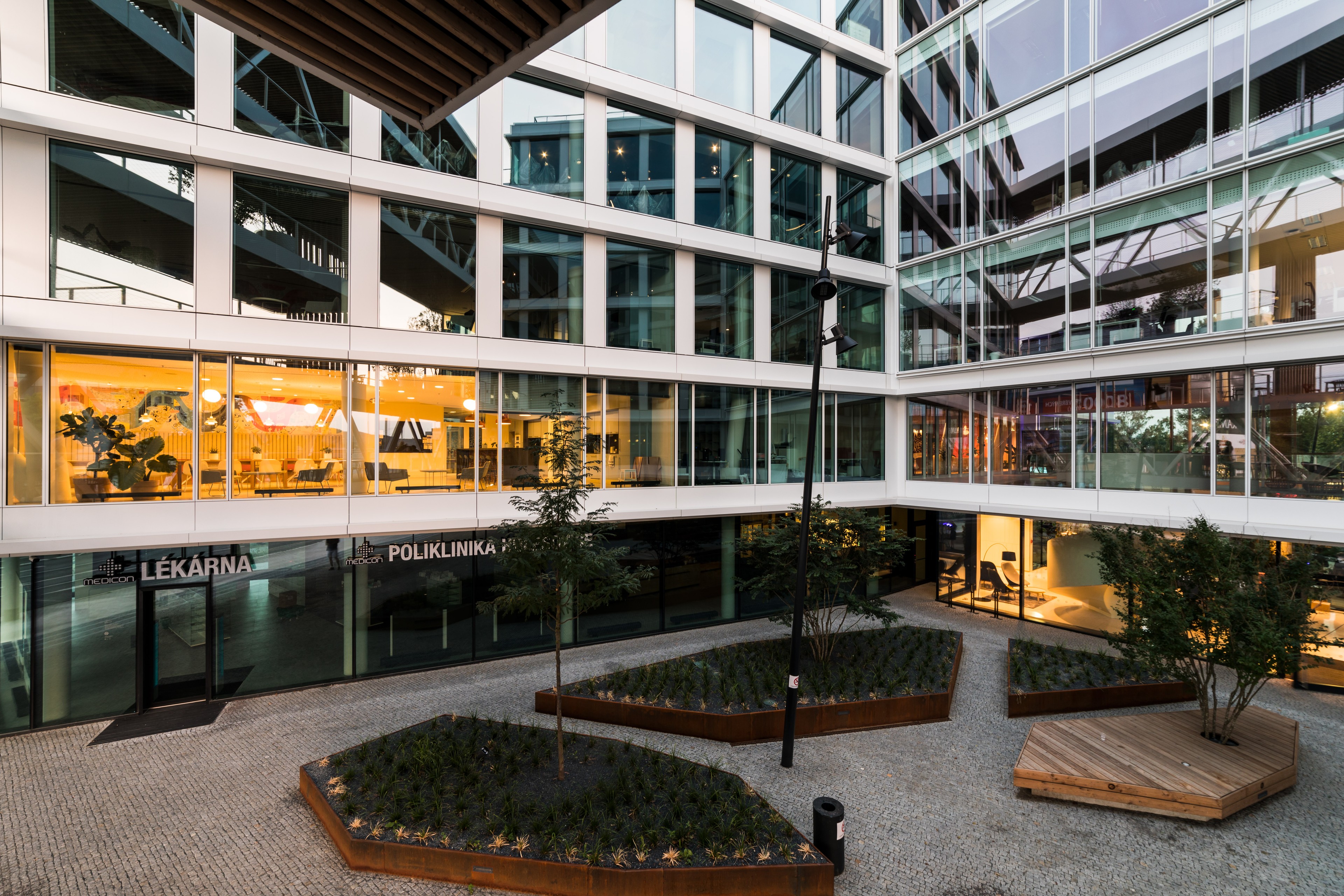 Outdoor space Courtyard of a modern office building with glass windows, indoor plants, and seating.