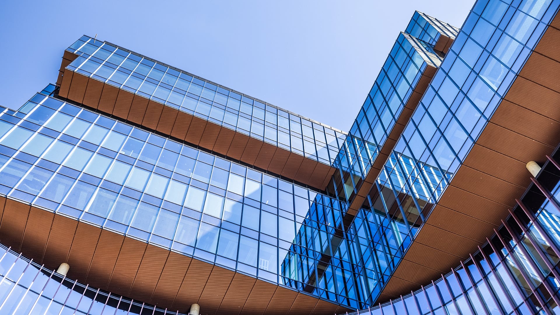 Modern Glass Architecture Against Clear Blue Sky Modern glass building with angular design and sky reflection under clear blue skies.