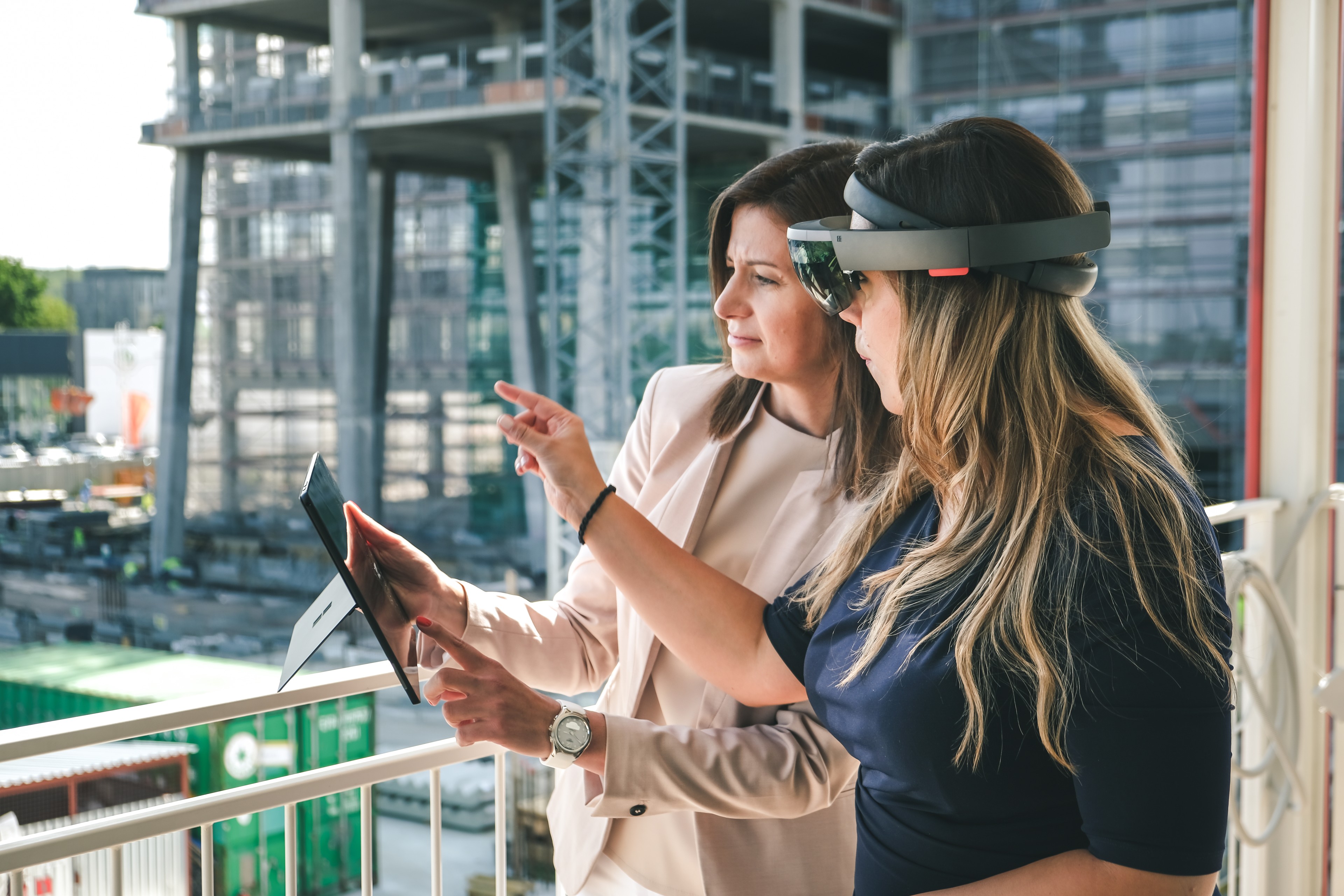 Inovace ve Skanska Dvě ženy používající tablet a headset pro rozšířenou realitu na staveništi.