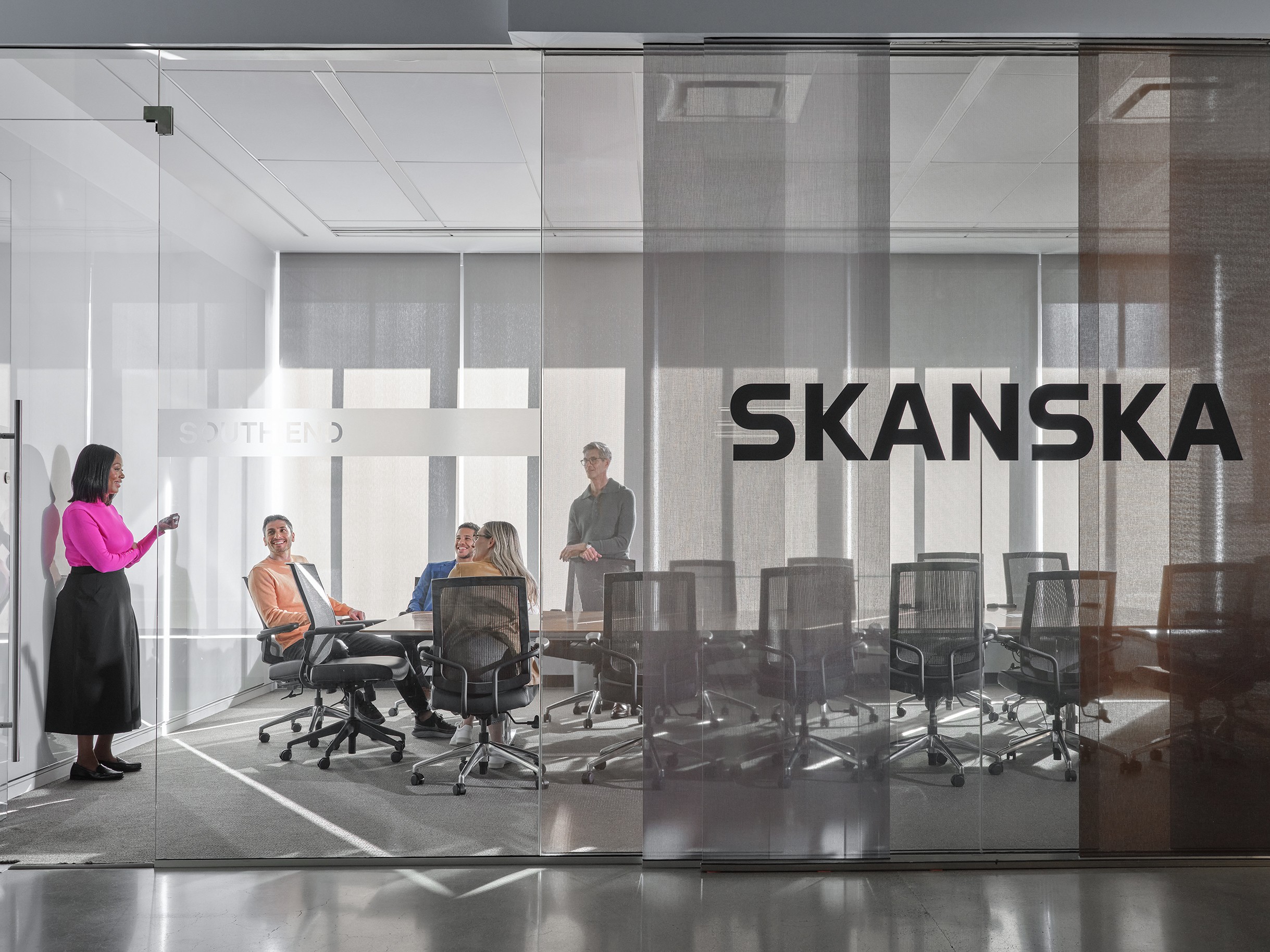 Modern Business Meeting at Skanska Office with Team Collaboration Moderní kancelářská schůzka s různorodým týmem uvnitř skleněné konferenční místnosti v sídle Skanska.