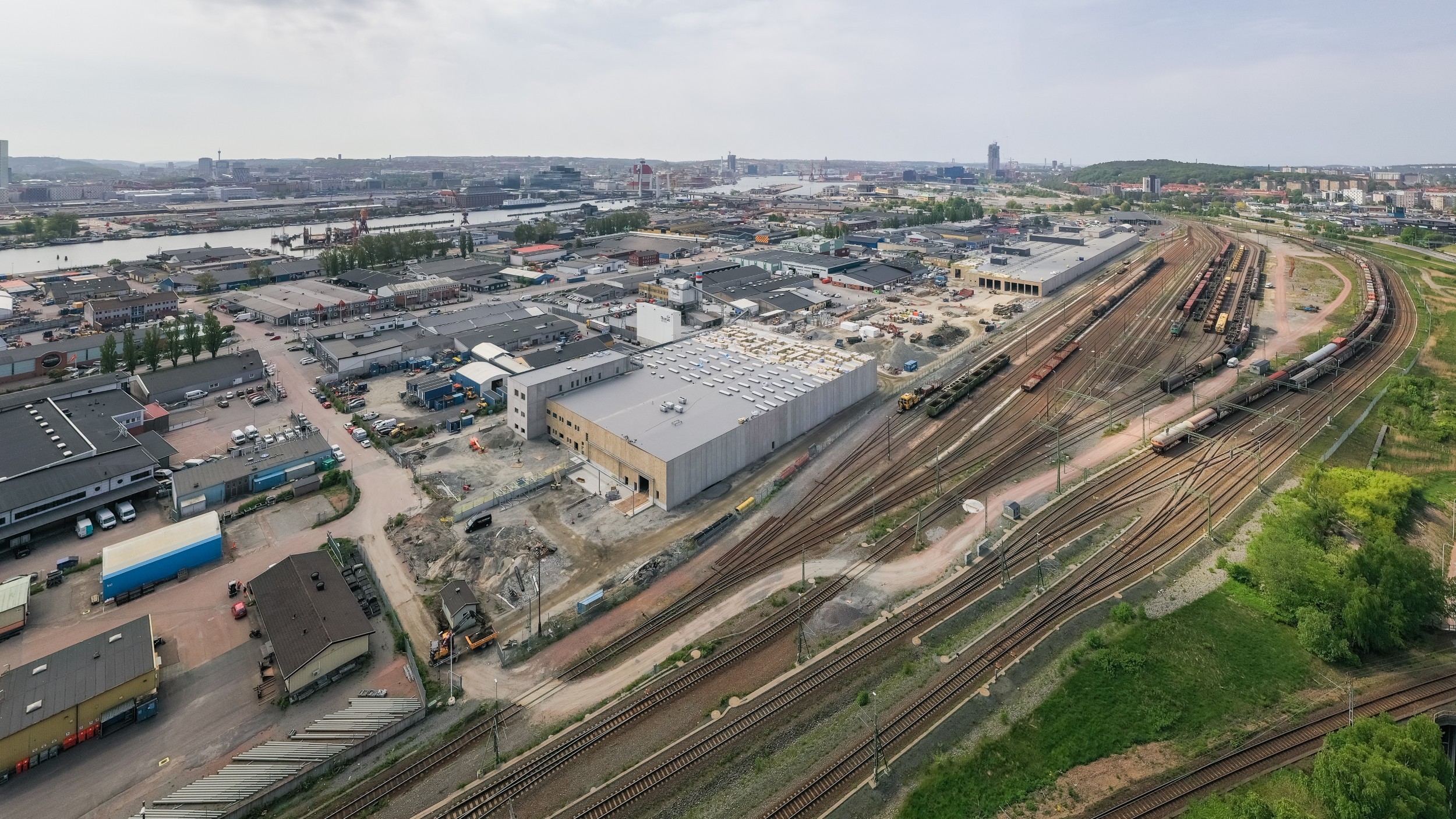 Flygvy över ett industriområde med järnvägsspår och lagerbyggnader under konstruktion.