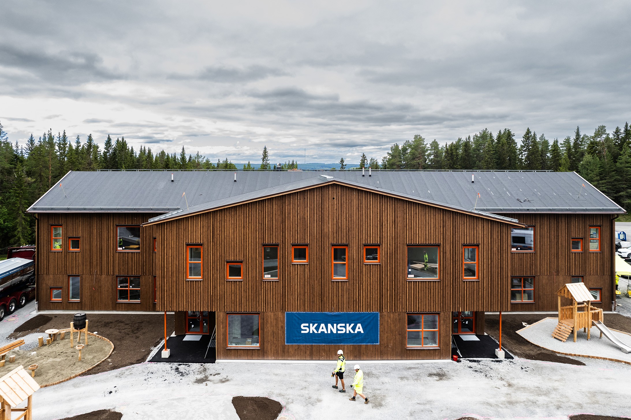 Vid Ottfjället i Östersund har Skanska byggt en ny förskola med högt ställda klimatkrav. Förskolan byggs enligt Skanskas ABCD-koncept som innebär en flexibel och kostnadseffektiv förskolelösning. Byggnad i två våningar med träfasad sedd från håll lite ovanifrån.