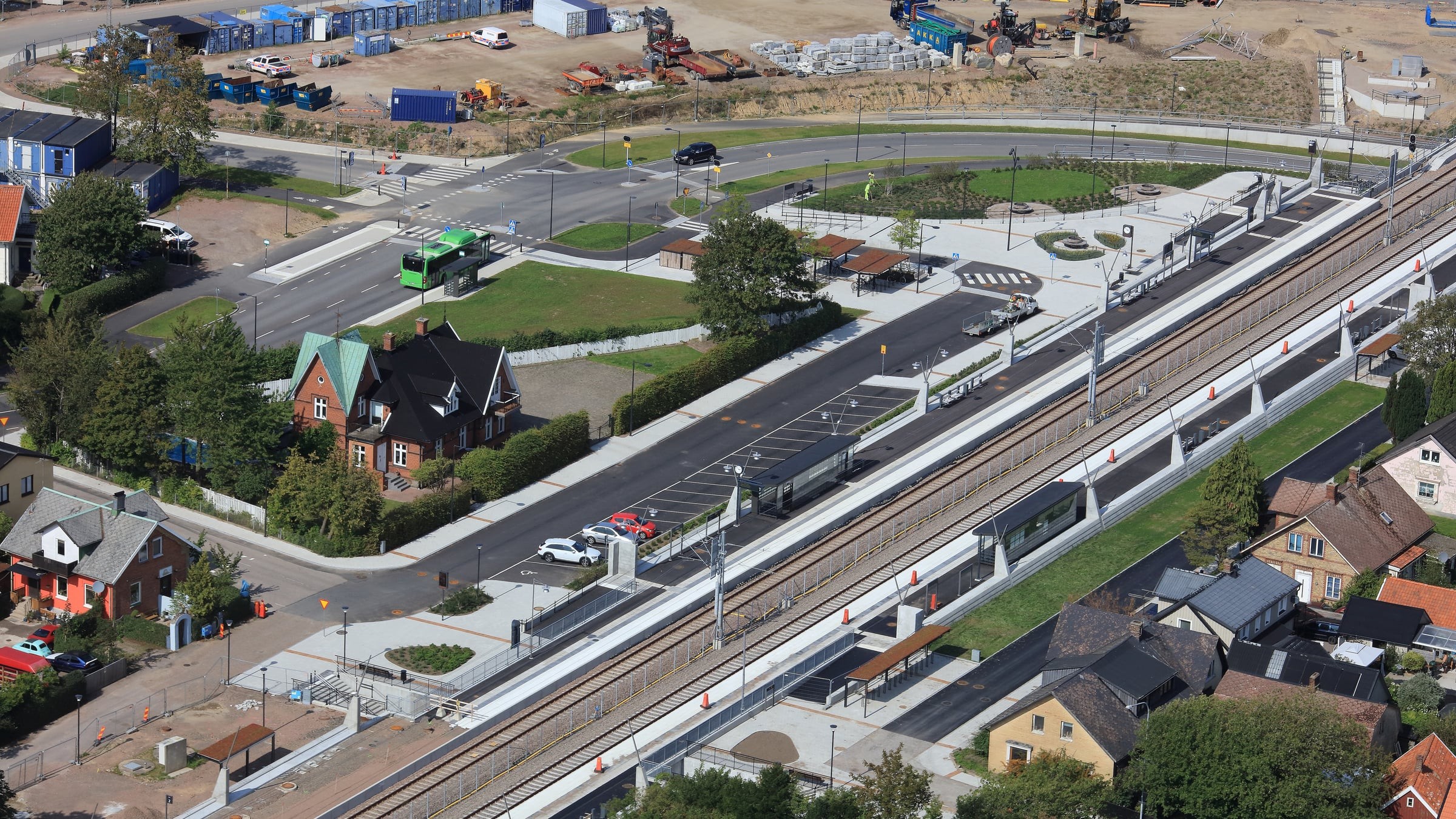 Järnvägsspår med stationsbyggnad, intill ligger bostäder och vägar.