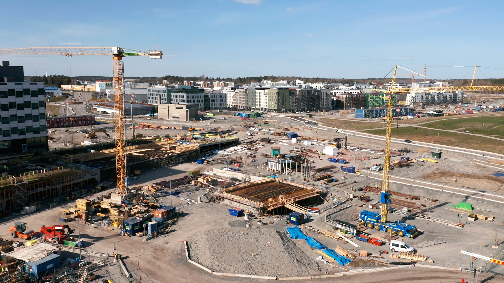 Armering pågår i Parkkvarteret som ska stå färdigt 2023. Flygvy över en stor urban byggarbetsplats med kranar och utrustning under klarblå himmel.
