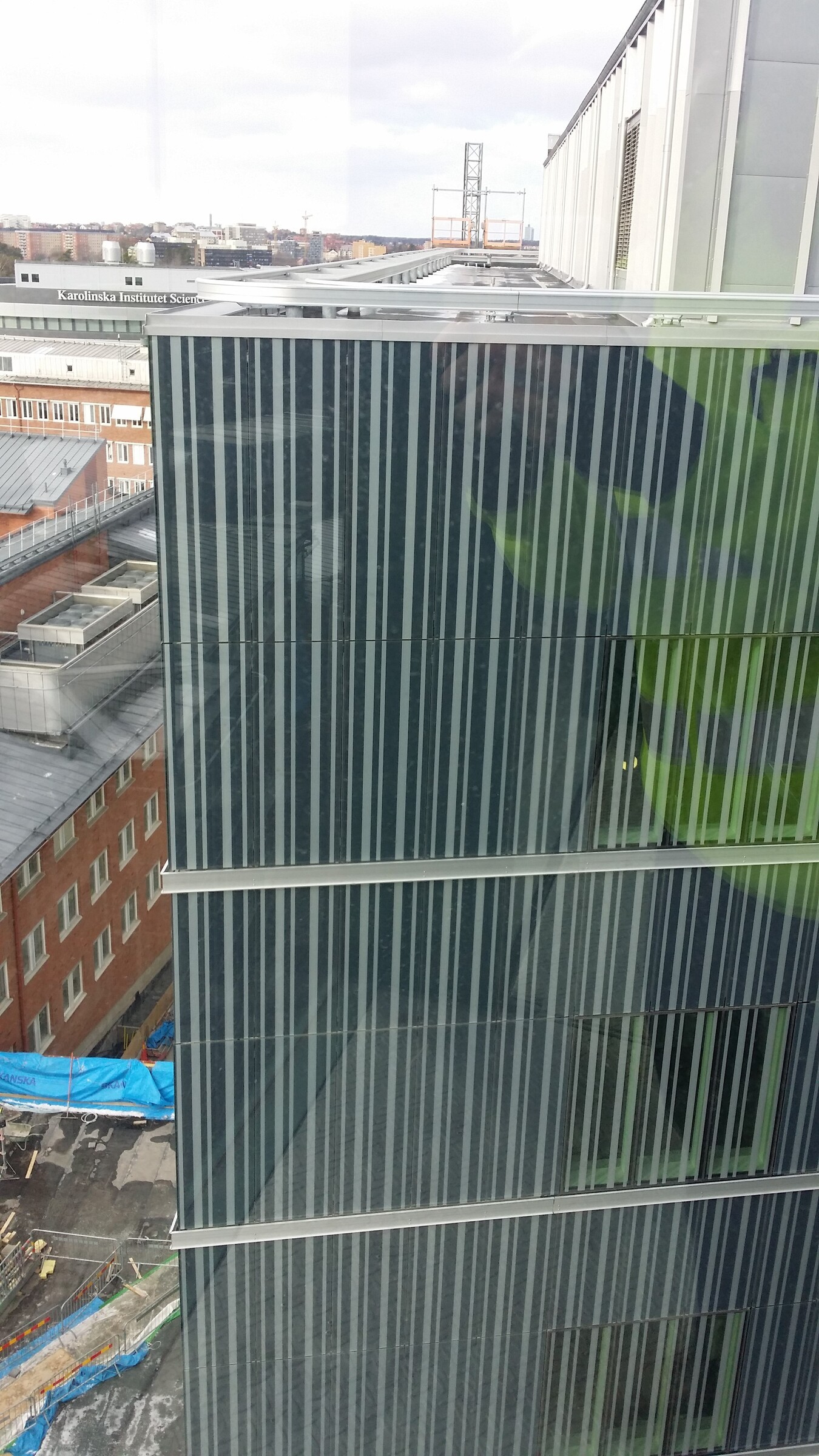Vy över modern byggnad med vertikal randig glasfasad som speglar omgivningen.