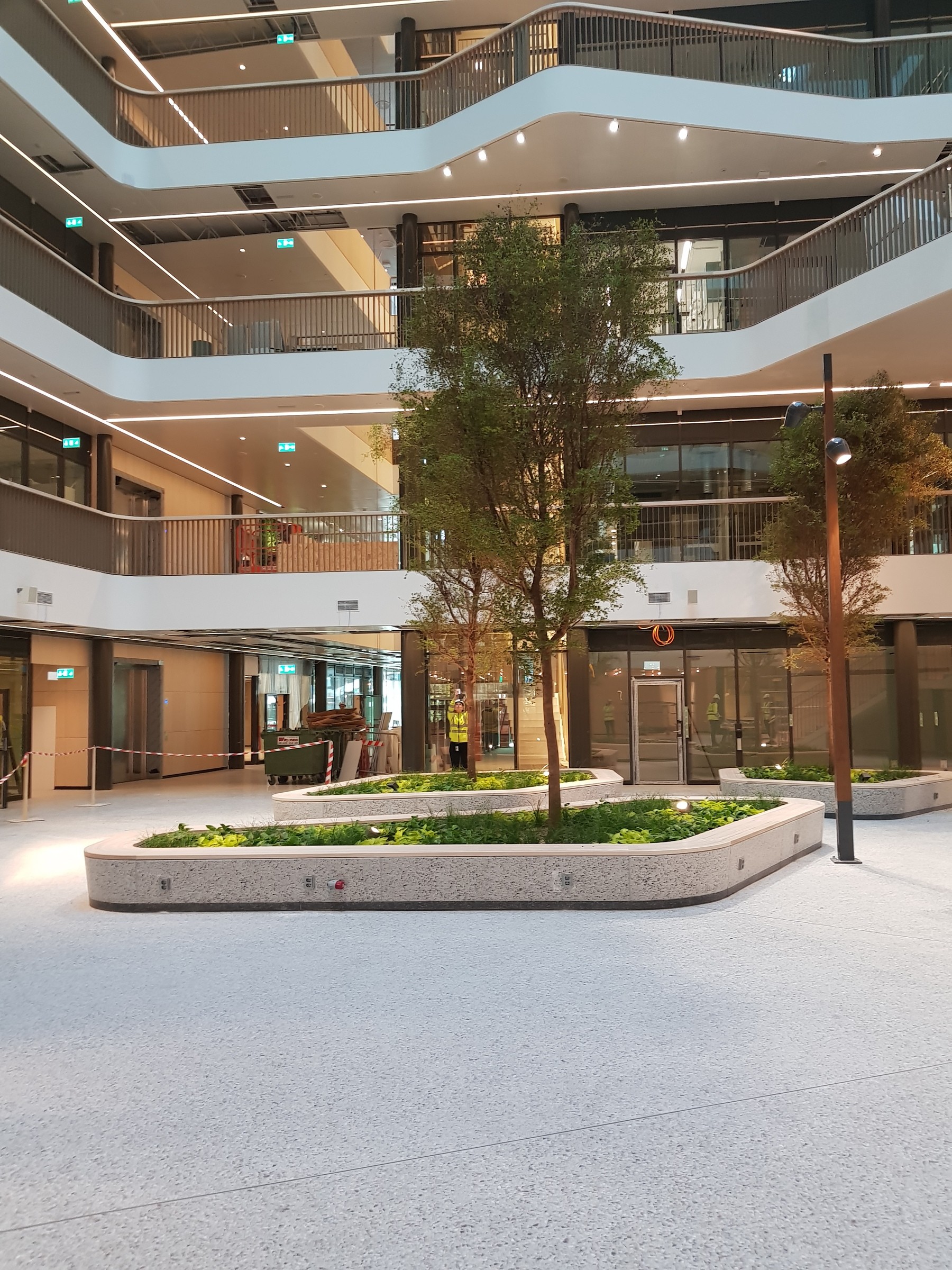 Biomedicum Modernt inomhusatrium med träd, grönska och flervåningsbalkonger i en slank arkitektonisk design.
