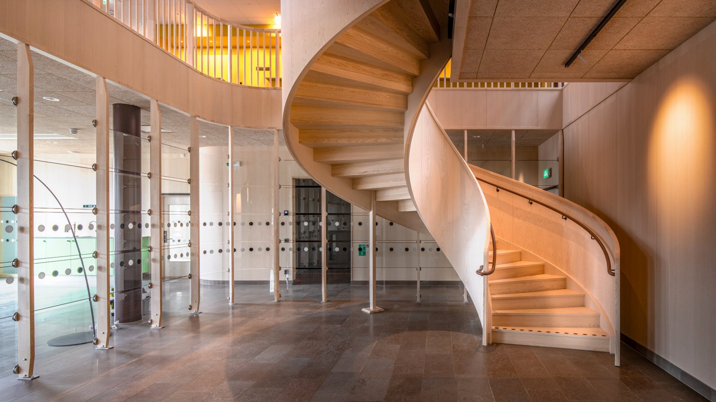 Materialvalen är ljusa och naturnära. Foto: Anders Bobert Invändig spiraltrappa i ljust trä i ett Boverkets huvudkontor med glasväggar.