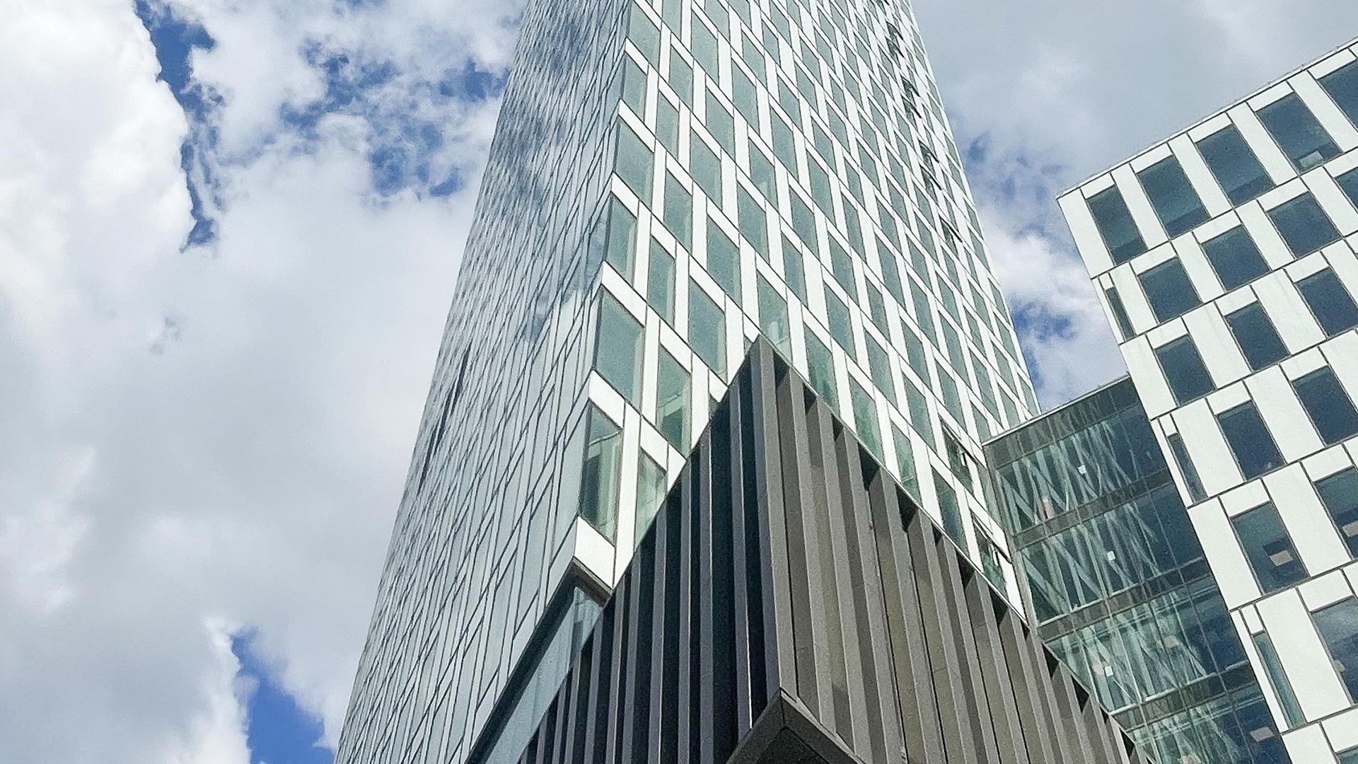 Fasader i olika vinklar och höjder i blank metall och vitt mot blå himmel och vita moln.