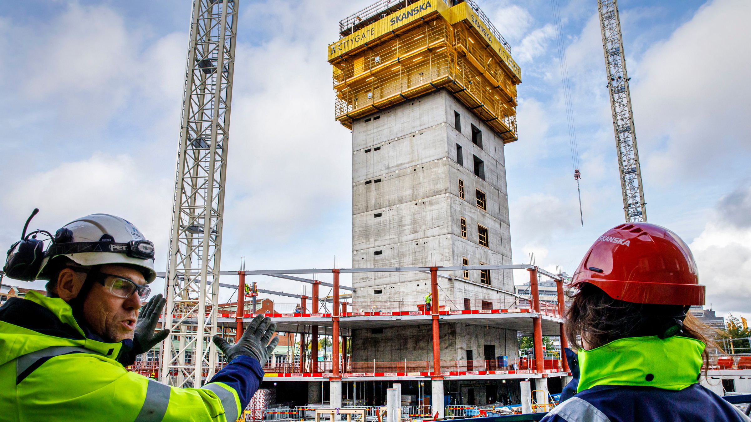 Byggnadsarbetare övervakar utvecklingen av en höghusbyggnad under konstruktion.