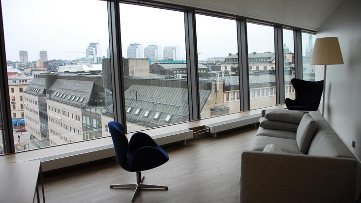 Clarion Sign Modern lounge med panoramautsikt över staden, med stilrena möbler och stora fönster från golv till tak.