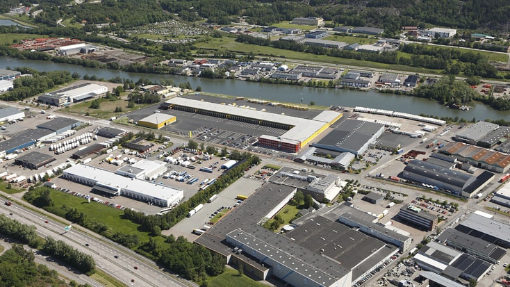 DHL Flygvy över ett industriområde med lagerbyggnader, fabriker och en flod som rinner längs med.
