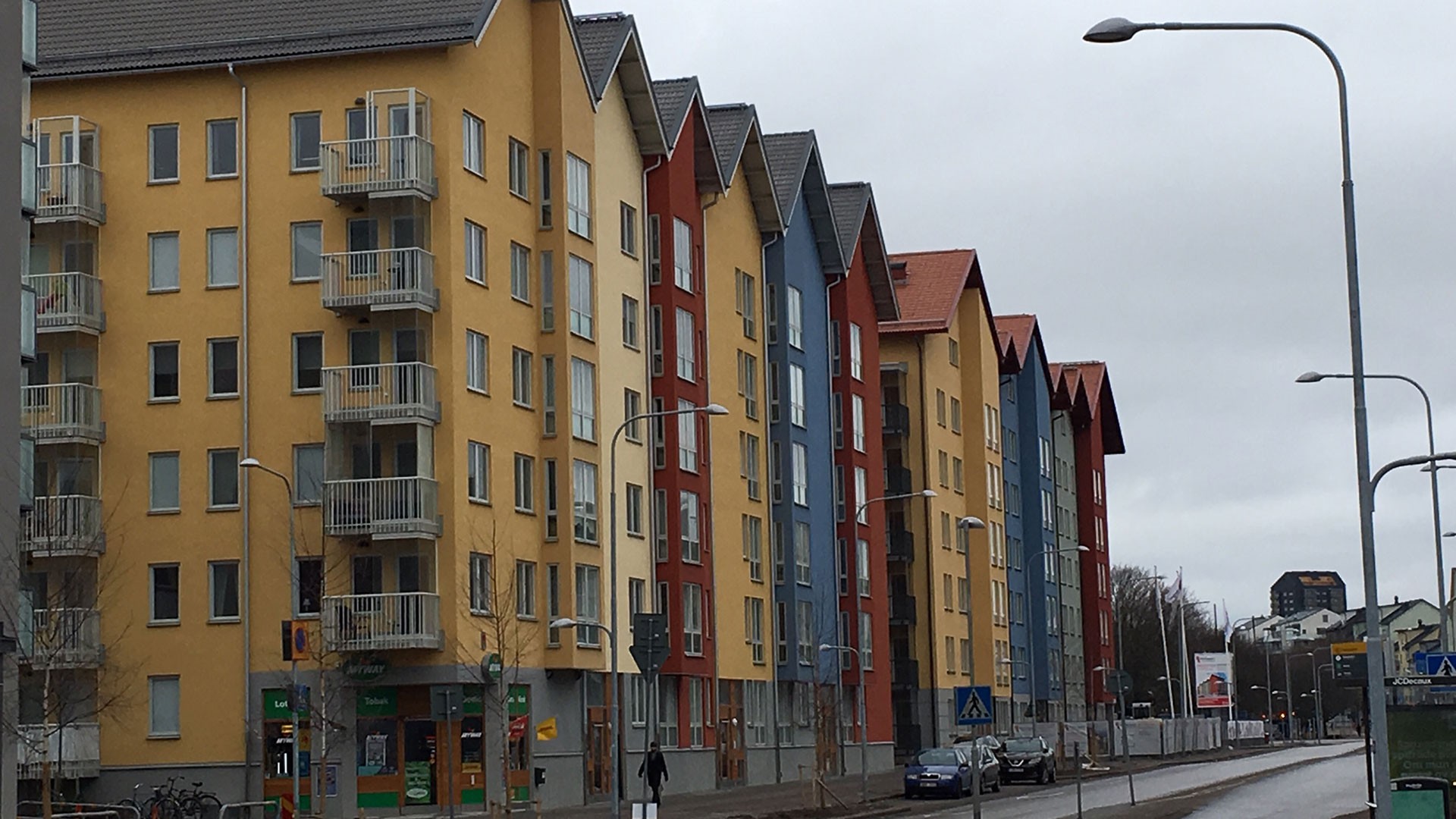 Färgglada, moderna lägenhetsbyggnader kantar en gata på en molnig dag och visar upp olika arkitektoniska stilar.