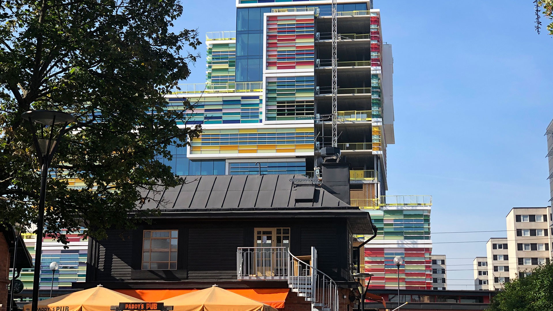 Läget, alldeles intill Sollentuna station, gör fastigheten lättillgänglig. Modern färgglad byggnad med geometriska mönster reser sig bakom en traditionell mörk träpub.