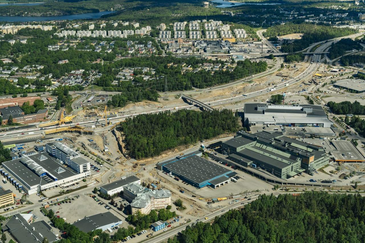 Flygvy över ett stadslandskap med byggarbetsplatser, industribyggnader och bostadsområden.