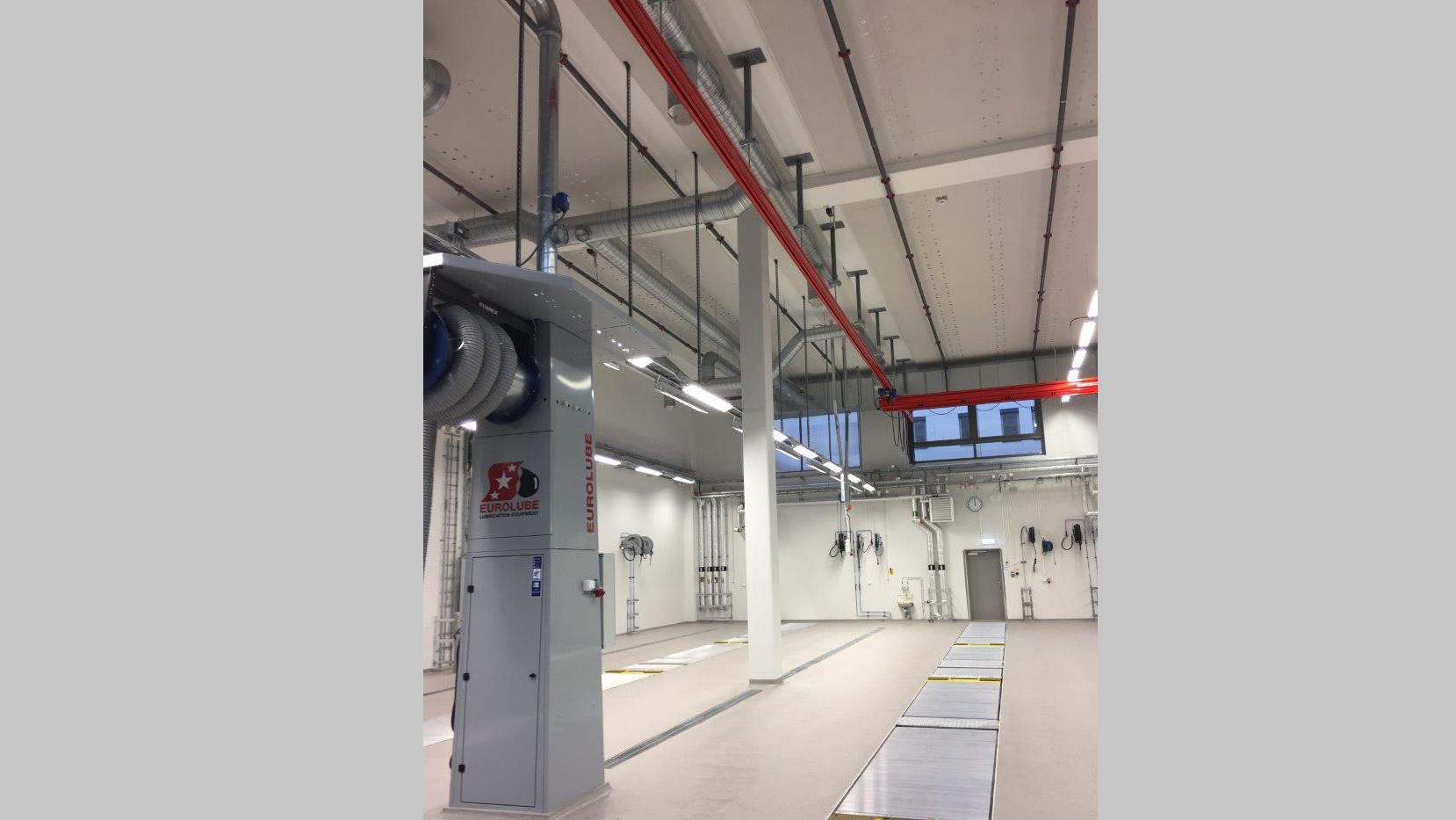 Det finns tvätthallar, garage och servicestationer i bussdepån. Industriell anläggningsinteriör med ventilationssystem, rör ovanför och rena arbetsstationer.