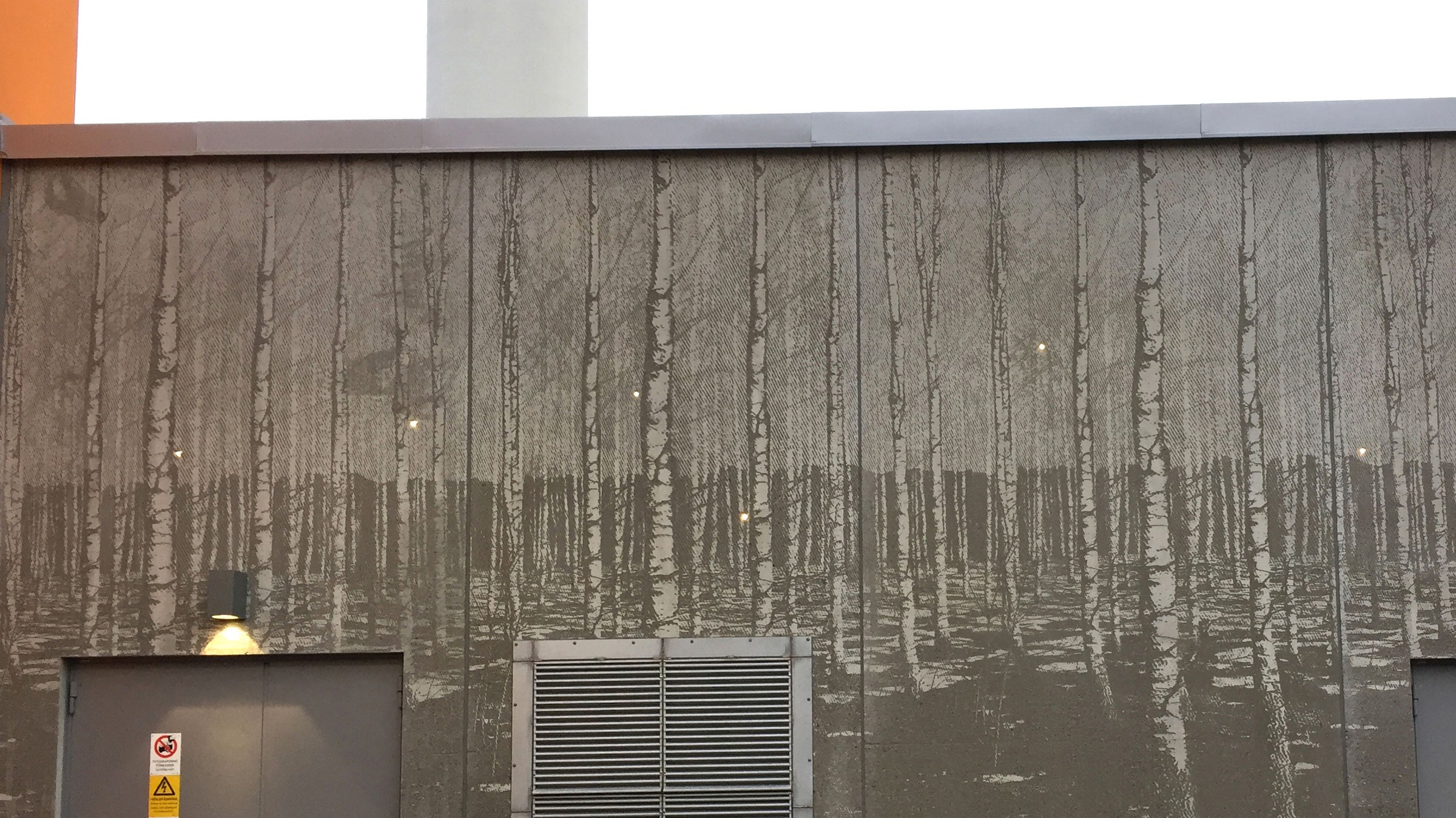 Fasaden är fint utsmyckad och små lampor lyser bland björkarna. En väggmålning som avbildar en tät björkskog, med industriella inslag som ventiler och lampor.