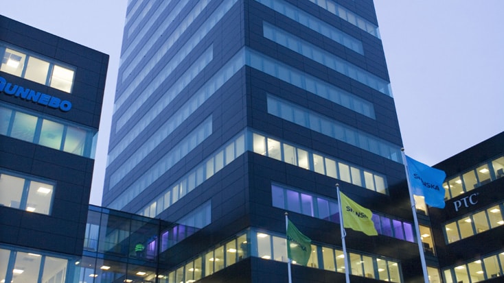Gröna Skrapan Modern höghus kontorsbyggnad med framträdande Dunnebo- och SKF-skyltar, omgiven av flaggor.