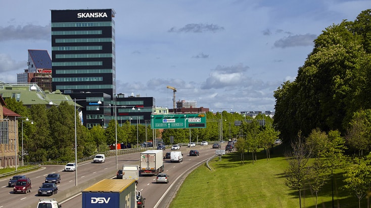 Gröna Skrapan Modern kontorsbyggnad, omgiven av parkerade bilar och frodiga gröna träd.