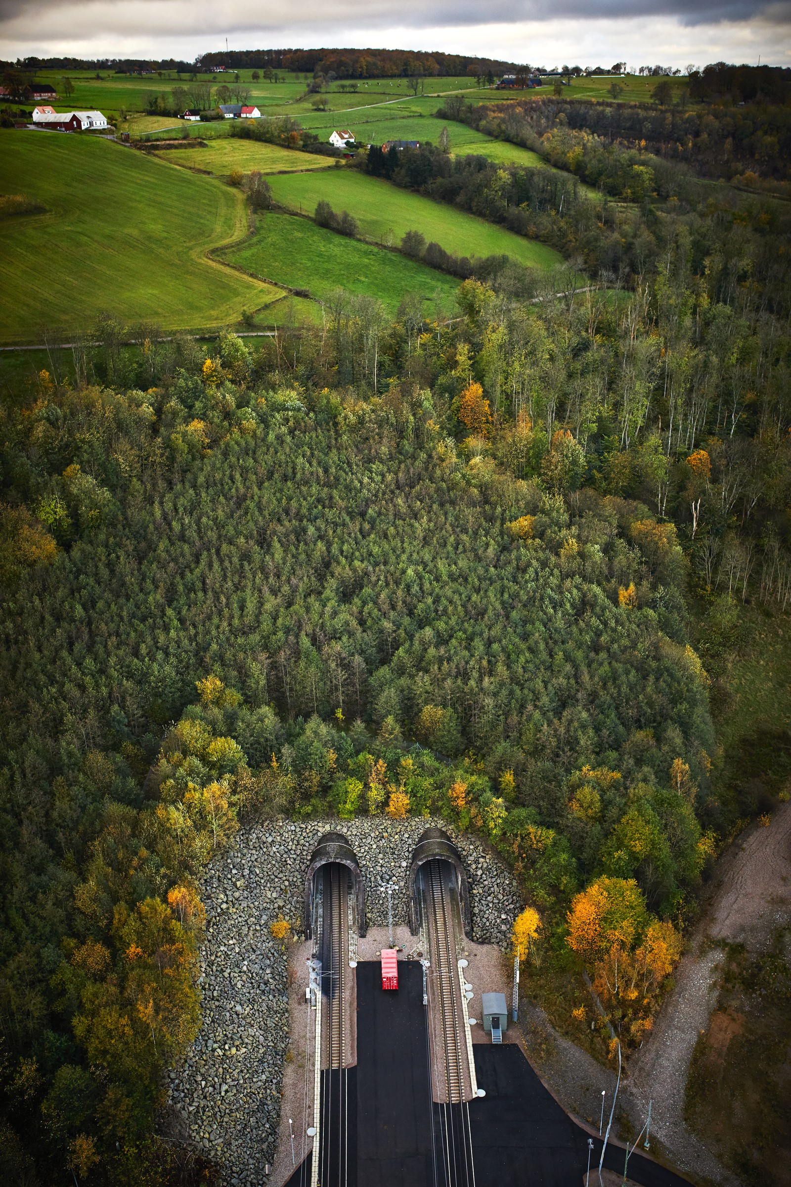 Hallandsås, flygfoto Flygvy över dubbla järnvägstunnlar i frodigt landskap med livlig höstlövverk och bondgårdar.