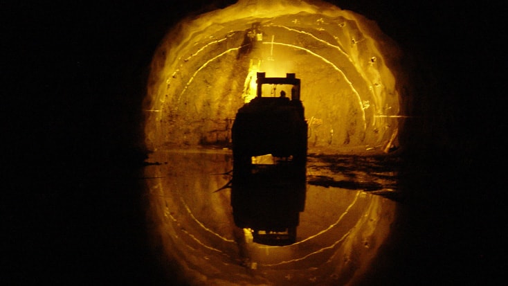 Hallandsås Silhuett av ett fordon i en svagt upplyst tunnel med reflekterande vatten på marken.
