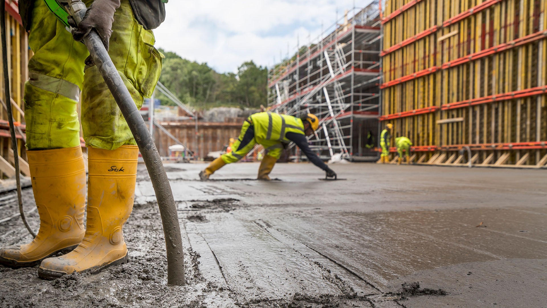 Efter nästan ett år av testning och dokumentation kunde Skanska börja gjuta betong med lägre klimatpåverkan på Hamnbanan i Göteborg. Gjutning av betong i en stor form. En person som man bara ser de gula stövlarna på fyller betong den andra slätar till den.