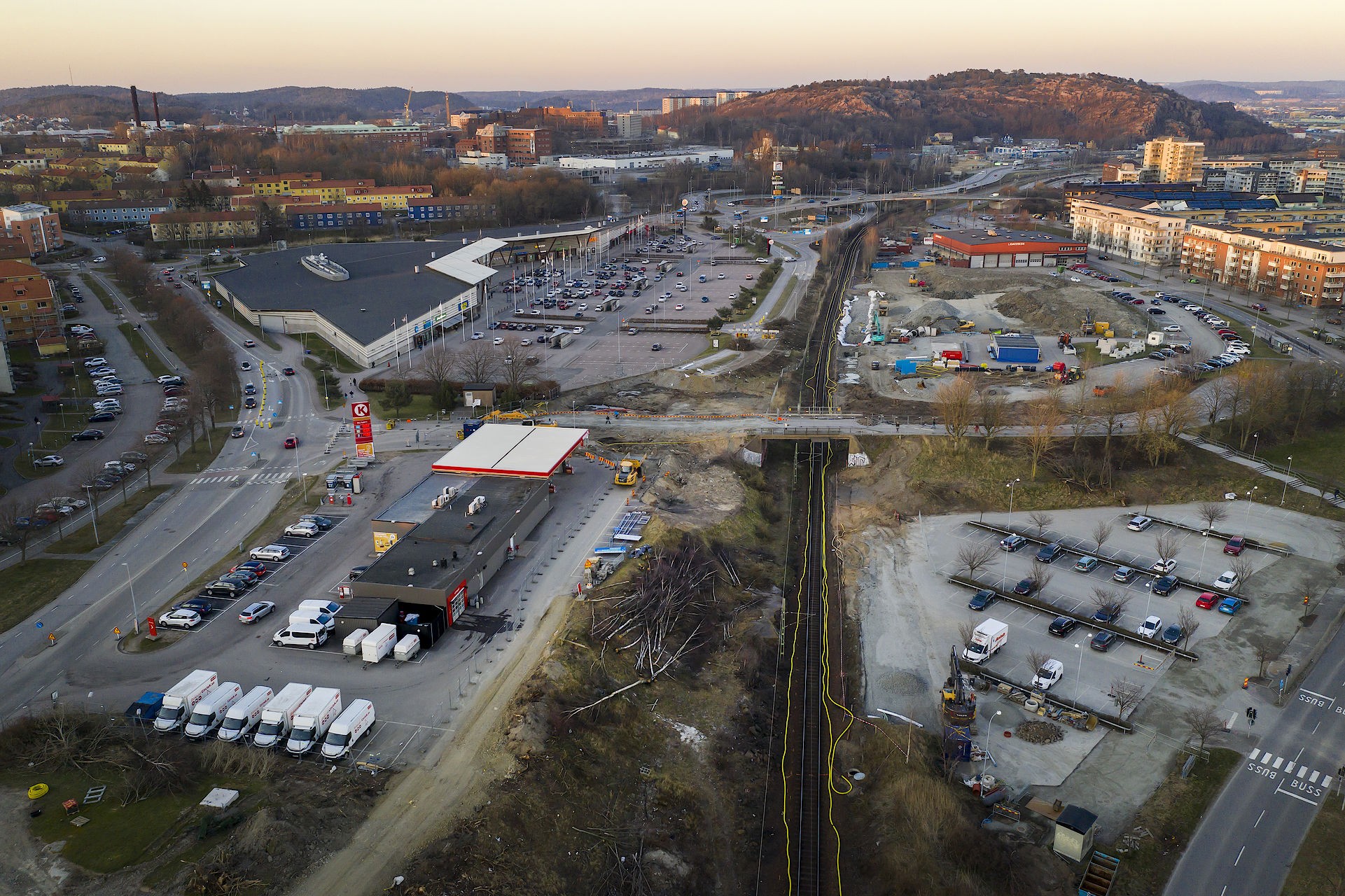 Skanska bygger ett nytt dubbelspår till Hamnbanan. Flygvy över ett livligt urbant område med vägar, en bensinstation och pågående byggnadsarbete.