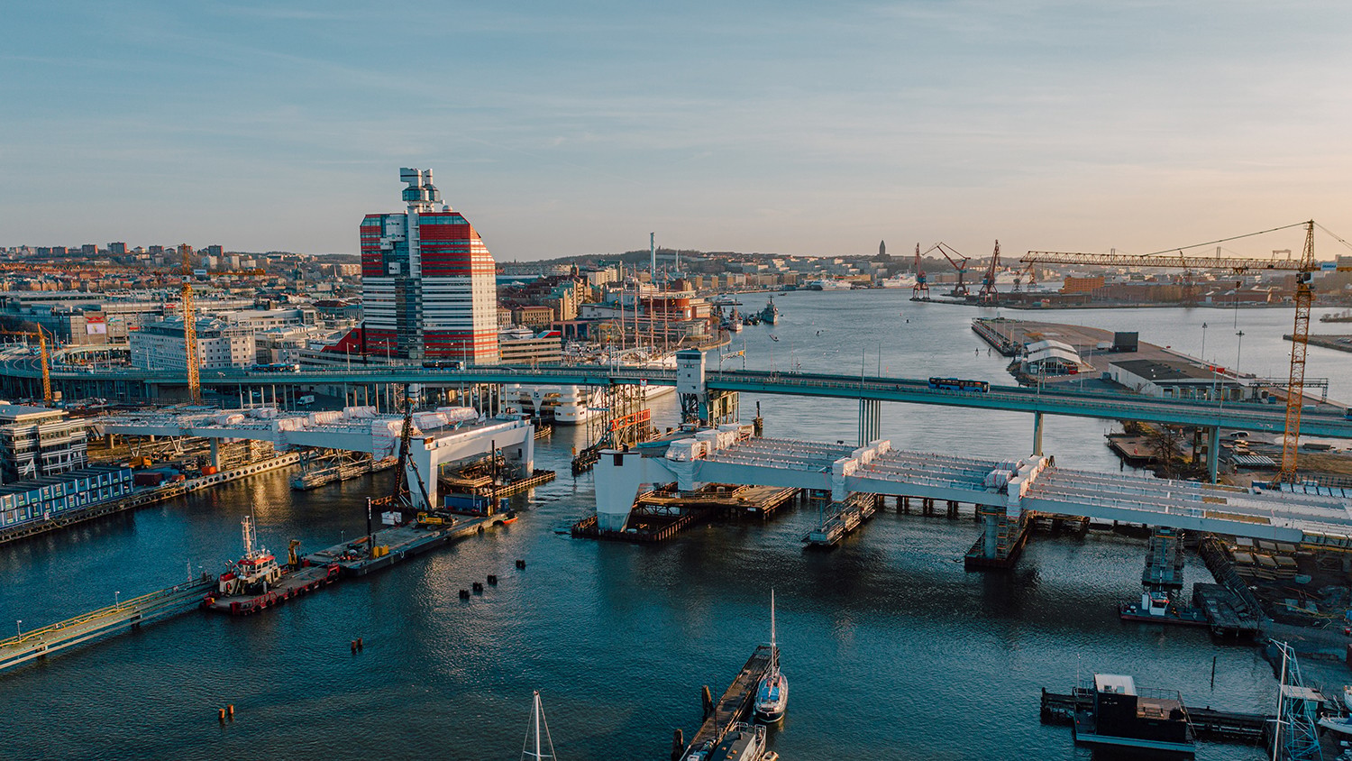 Flygvy över Göteborgs hamn med kranar, broar och den iögonfallande rödvita byggnaden.