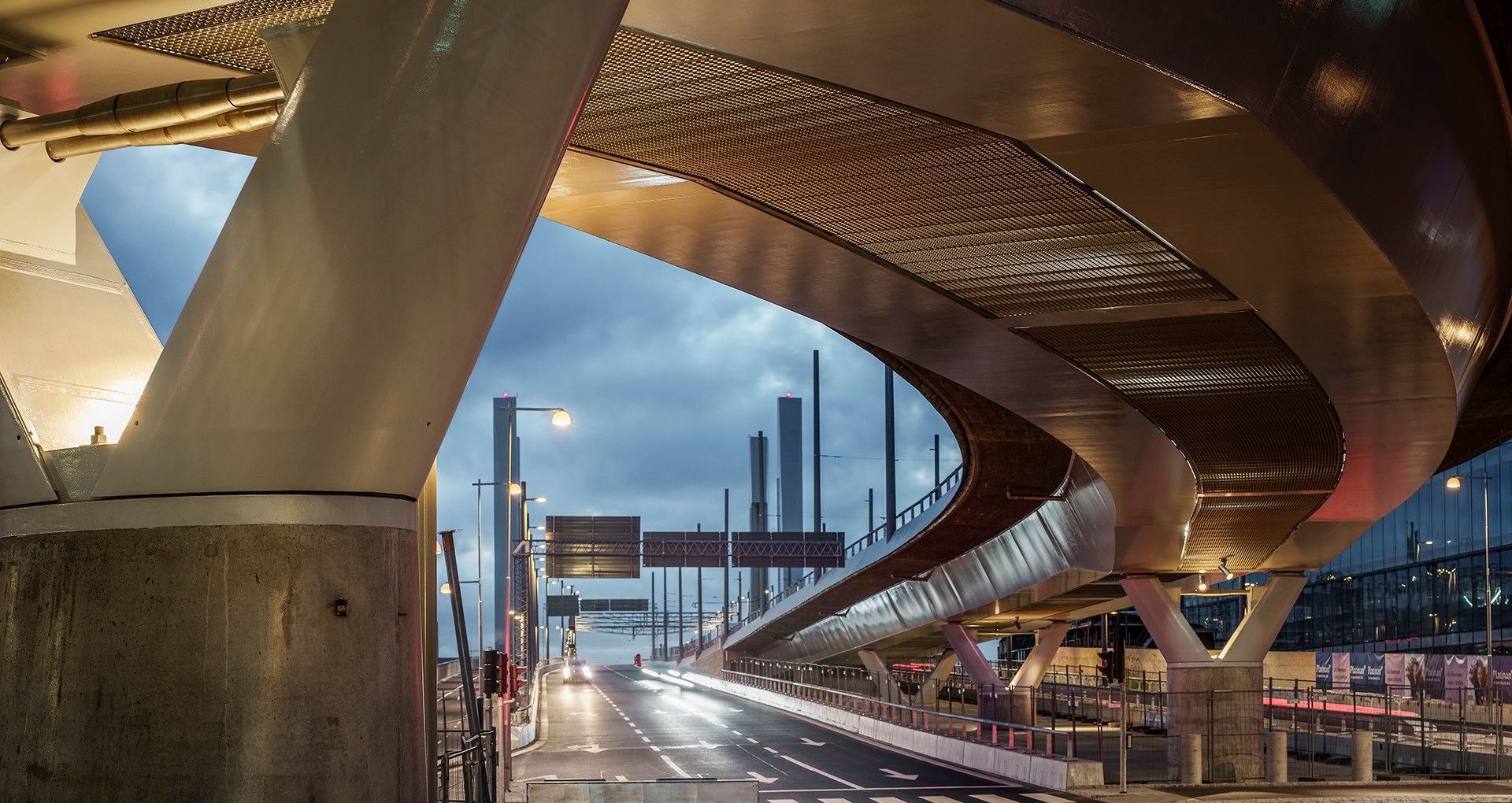 Modern urban bro med eleganta kurvor upplyst i skymningen, som visar arkitektonisk innovation.