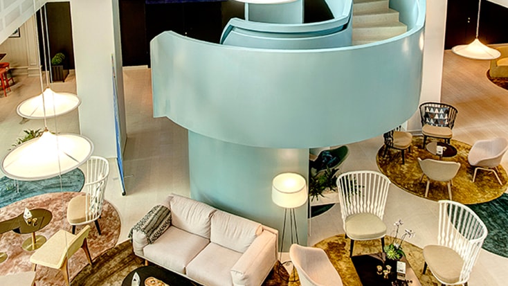Ideon Gateway Modern hotellobby med stilfulla möbler, spiraltrappa och eleganta belysningsarmaturer.