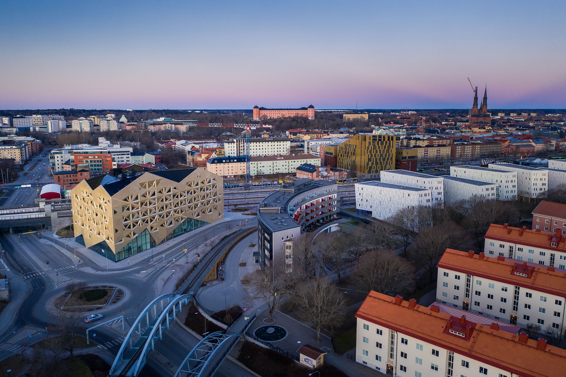 Flygvy över Uppsala som visar modern arkitektur tillsammans med historisk stadsbild i skymningen.