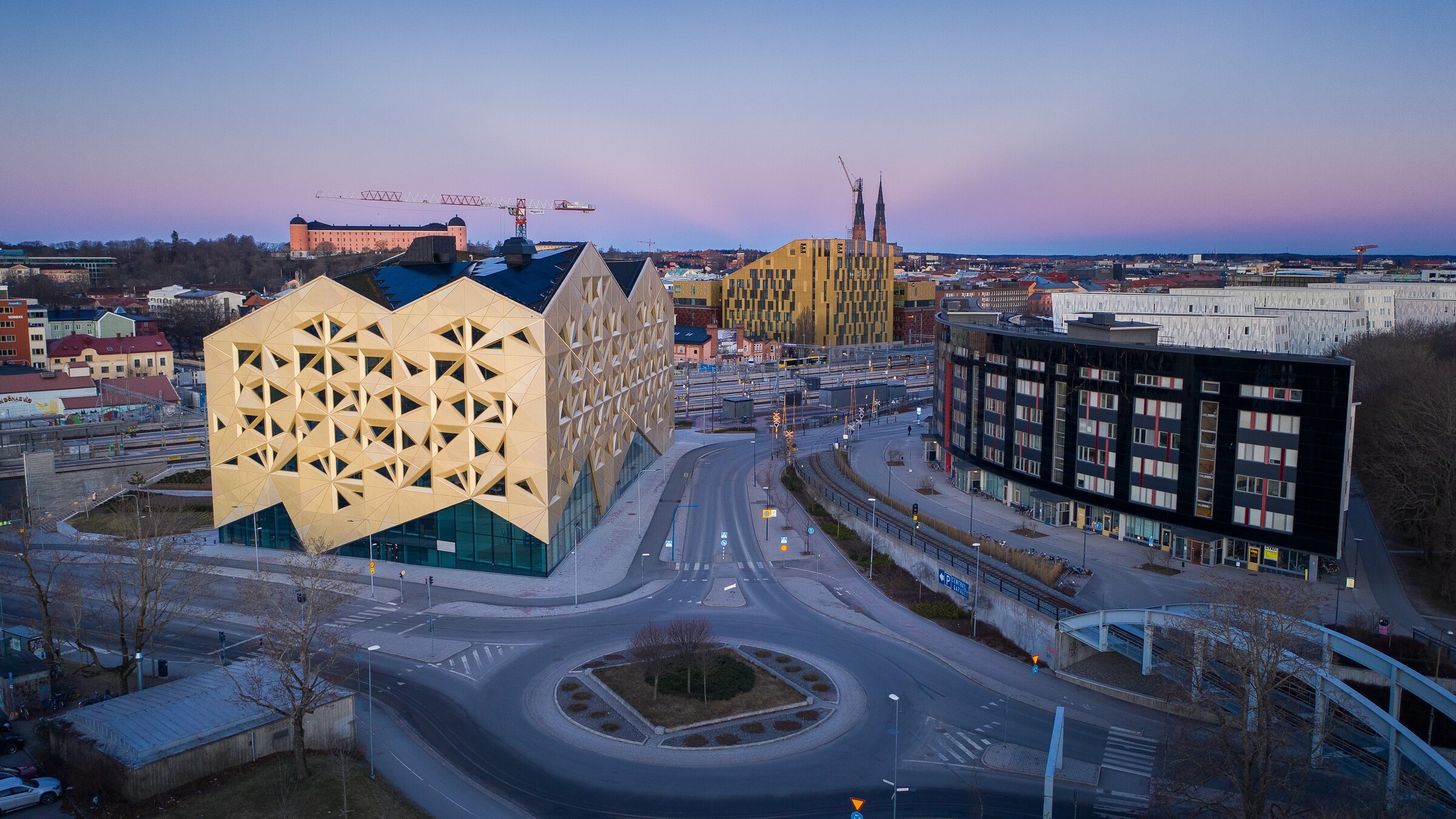Moderna arkitektoniska byggnader i en stadsbild vid skymning med en klar himmel i bakgrunden.