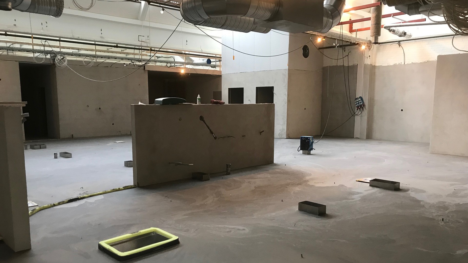 Industriellt utrymme under konstruktion med synliga kanaler och ofärdigt betonggolv.