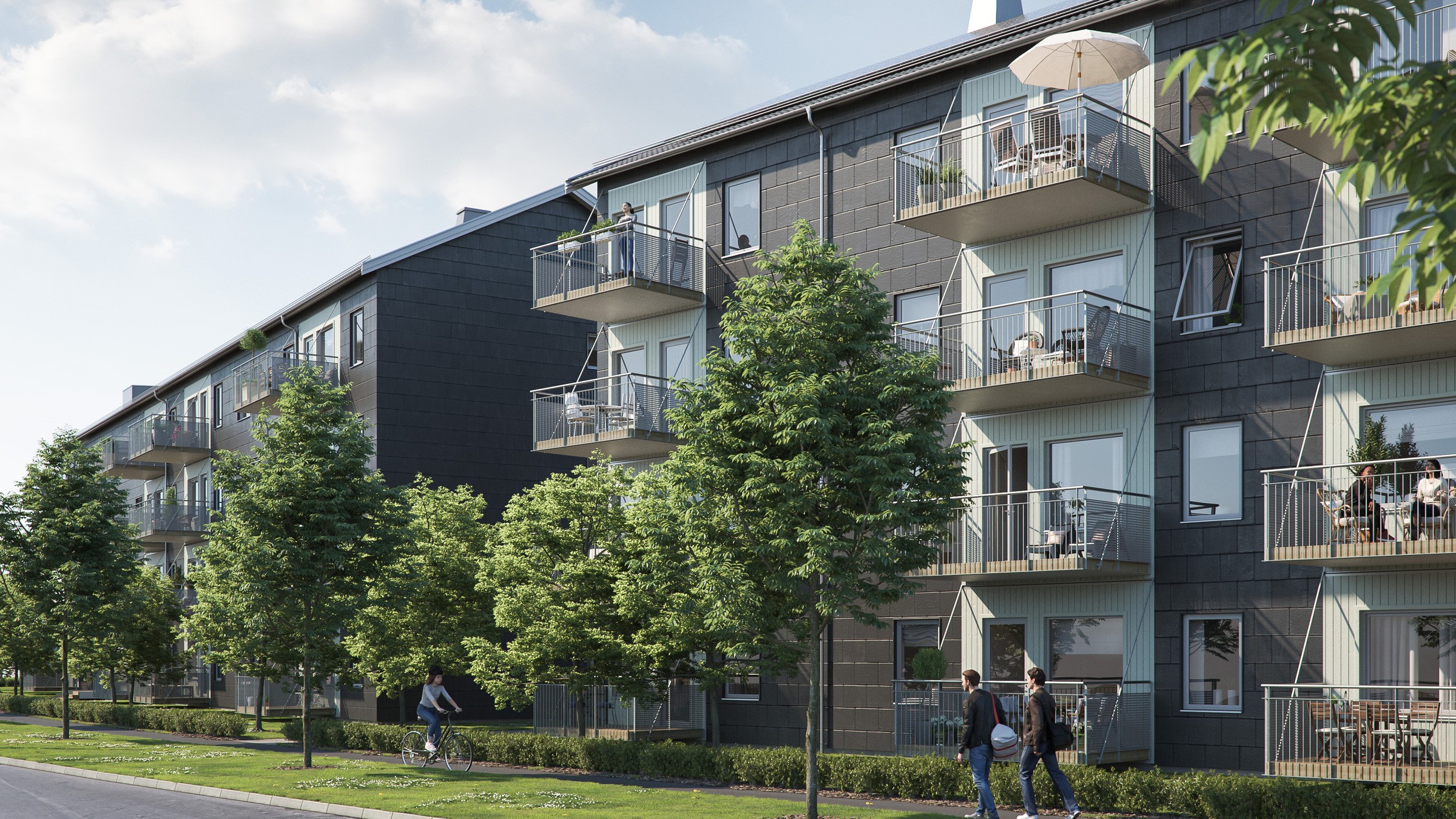 Modern lägenhetsbyggnad med balkonger och gröna träd längs trottoaren under en blå himmel.