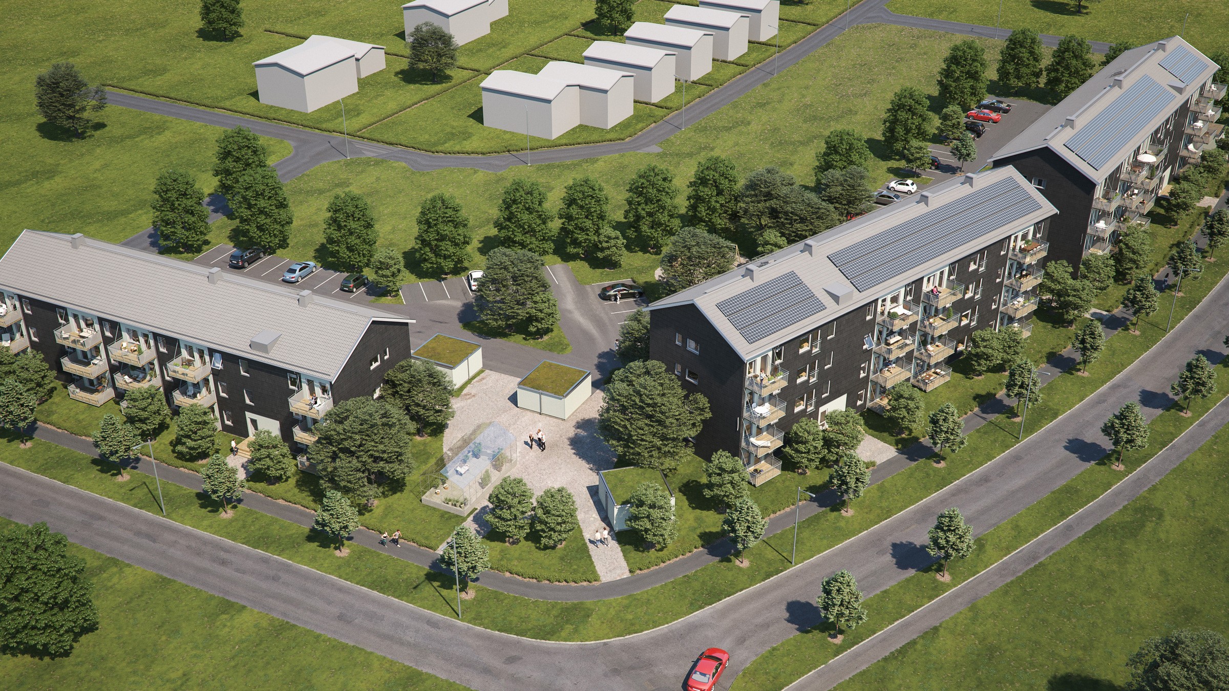 Flygvy över modernt bostadskomplex omgivet av grönska med parkering och gångvägar.
