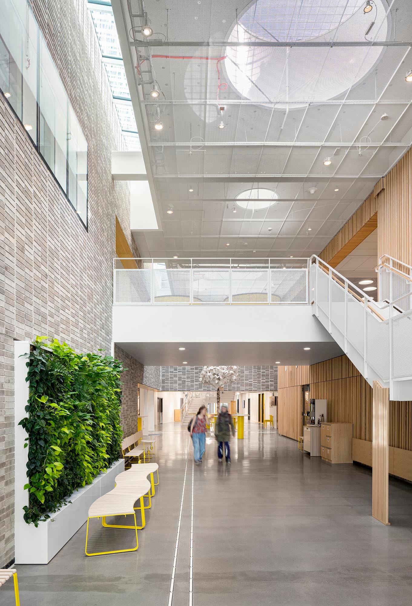 Modern lobby med högt i tak, takfönster, vertikal trädgård och eleganta möbler.