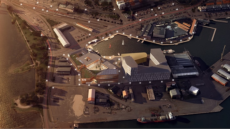 Flygvy över en strandnära utveckling med modern arkitektur och omgivande infrastruktur.