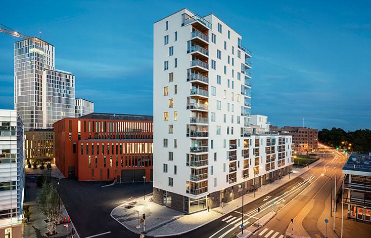 Modern stadsbostad med balkonger, omgiven av stadsgator och höga byggnader.