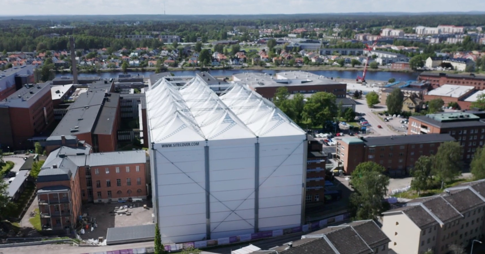 Under väderskyddet fortsätter arbetet med nya mottagningshuset för Karlstad centralsjukhus precis som vanligt, oavsett väder. En typ av stort vitt tält uppsatt över bygget.