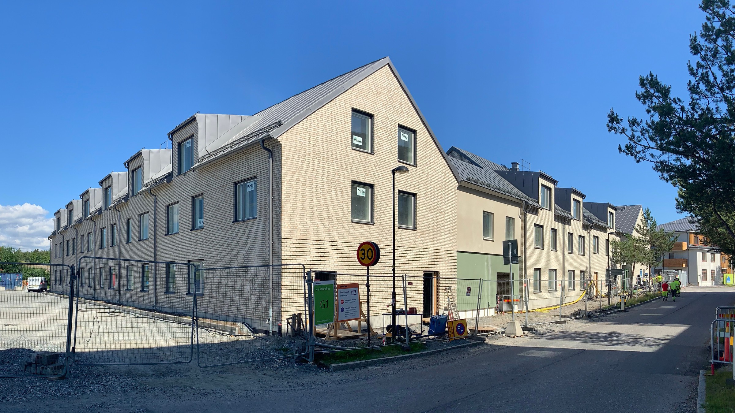 Nybyggd modern lägenhetsbyggnad med tegelfasad under en klarblå himmel.
