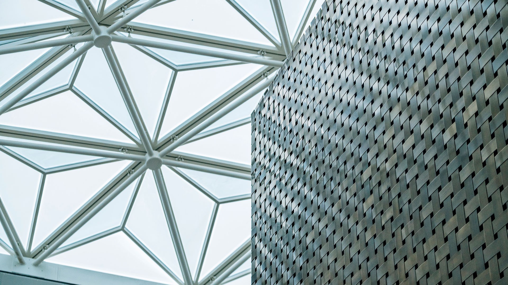 Modern arkitektonisk design med ett geometriskt glastak och texturerad vägg.