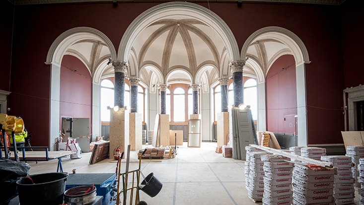 Renovering av en stor sal med valv, kolonner och byggmaterial i en historisk byggnad.