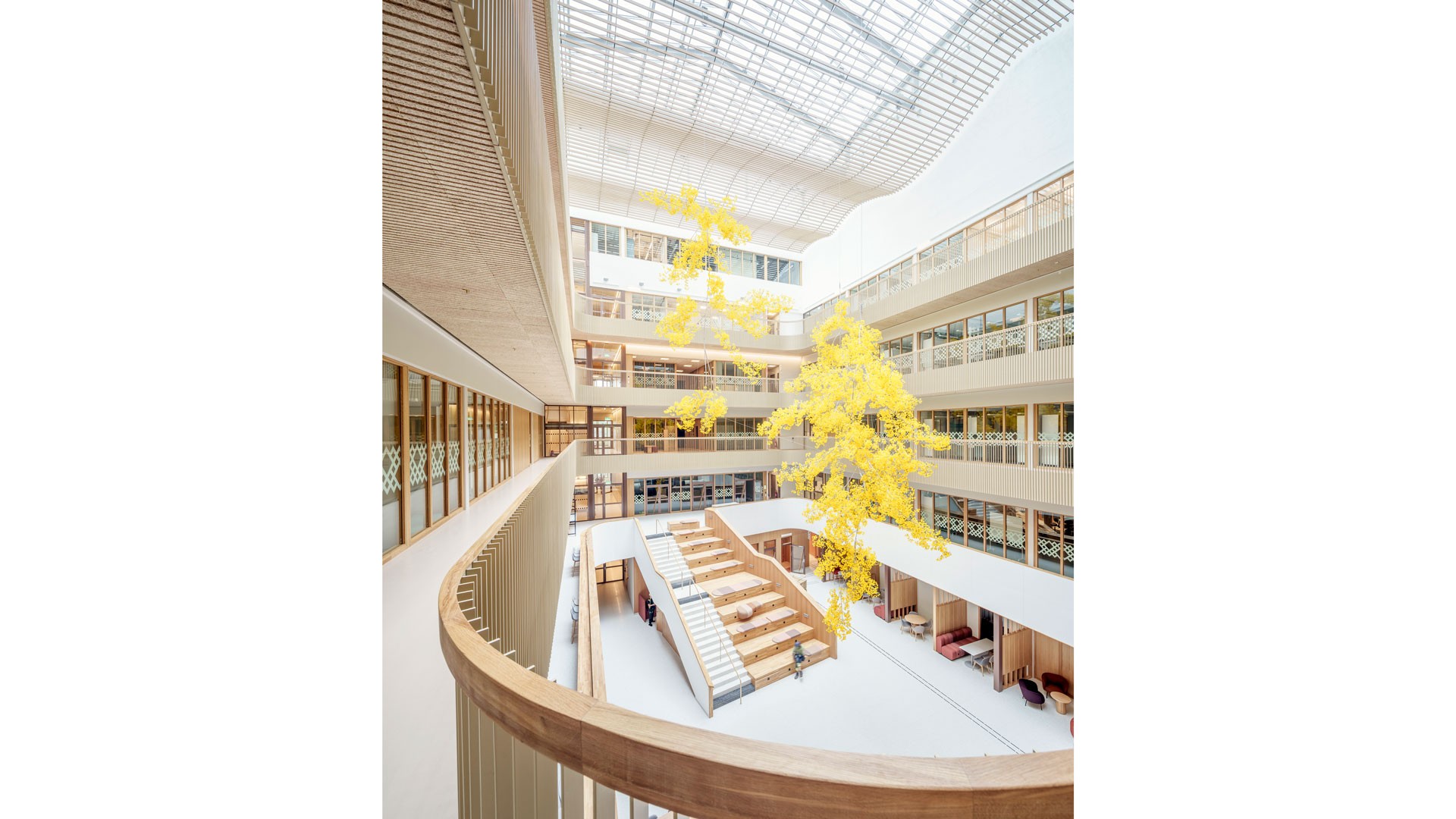 Modernt atrium med stort takfönster, med livfulla gula skulpturer och elegant arkitektonisk design.