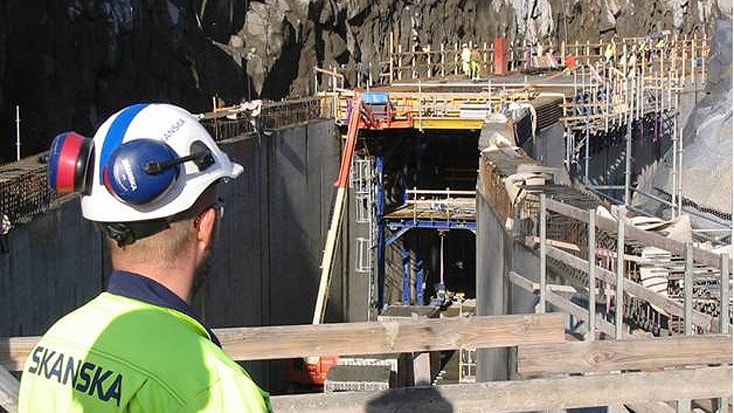 Norra Länken 11 Byggnadsarbetare som övervakar ett stort infrastrukturprojekt i ett klippigt område, iklädd skyddsutrustning.