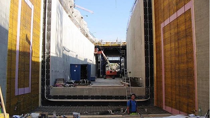 Norra Länken 11 Byggarbetsplats som visar stora betongkonstruktioner, med byggnadsställningar och en arbetare i förgrunden.