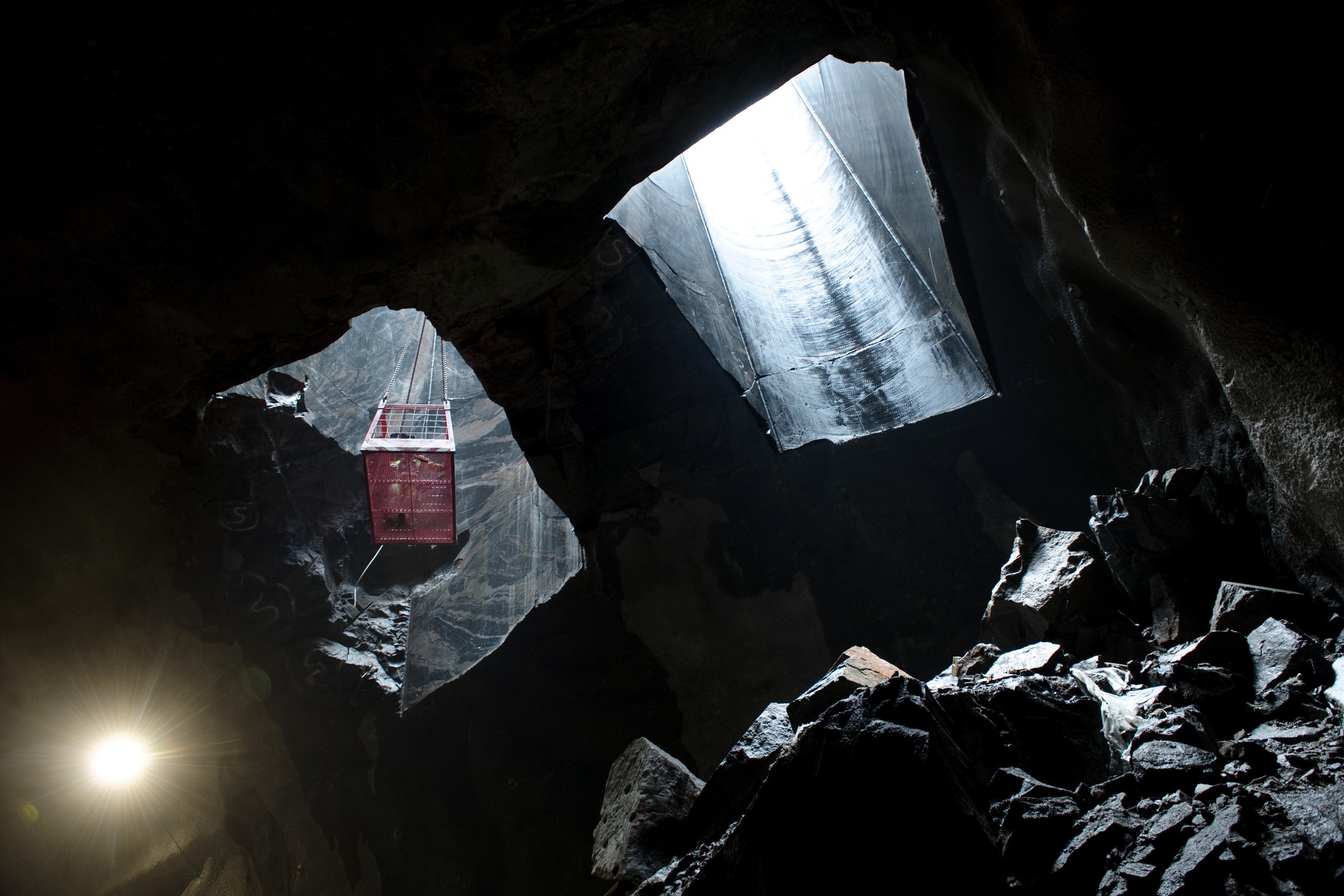 Arbetet med depån pågick dygnet runt. En röd låda är upphängd i en mörk, stenig grotta, upplyst av en ljusstråle från ovan.