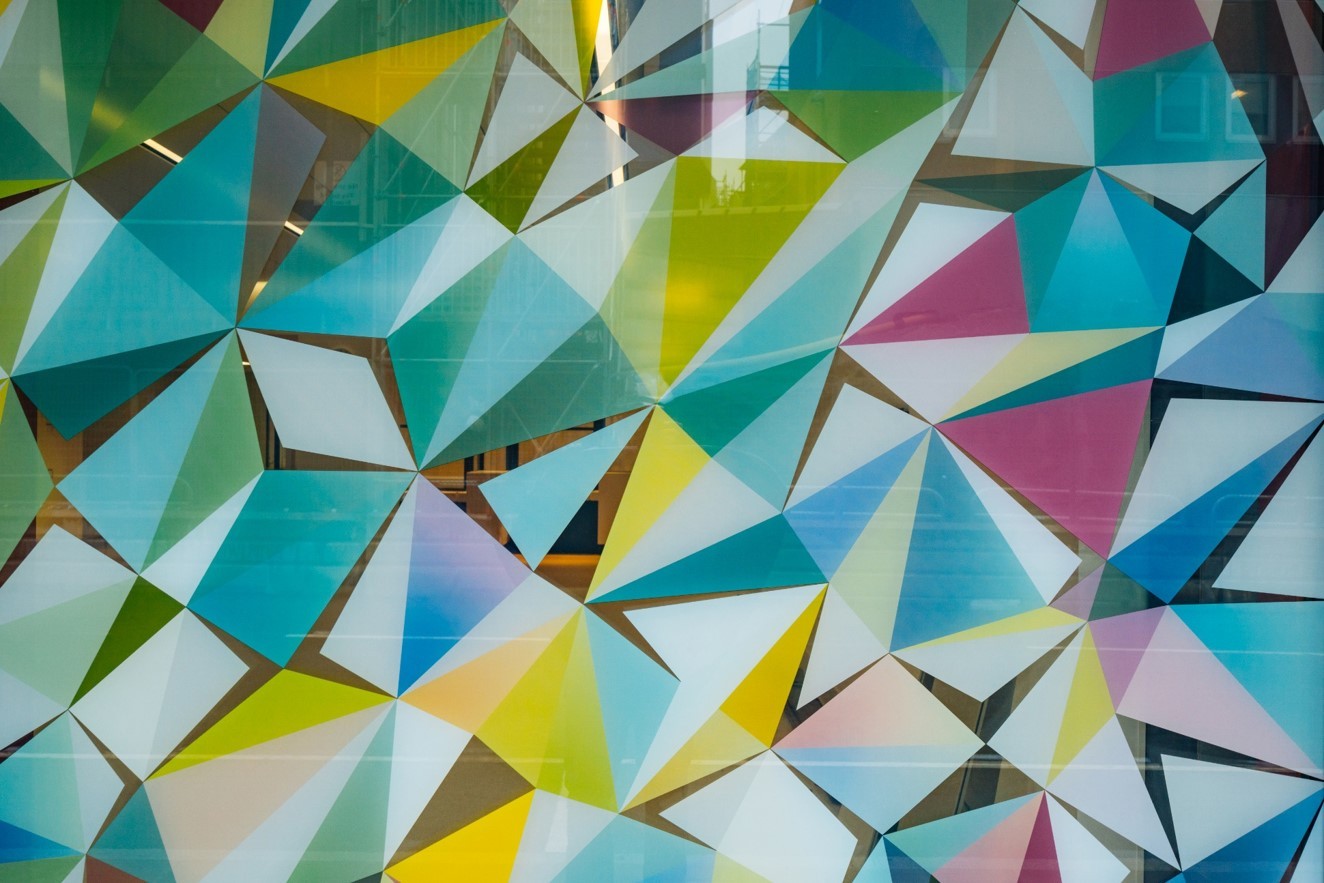 Färgglatt geometriskt mönster av överlappande trianglar på en glasyta.