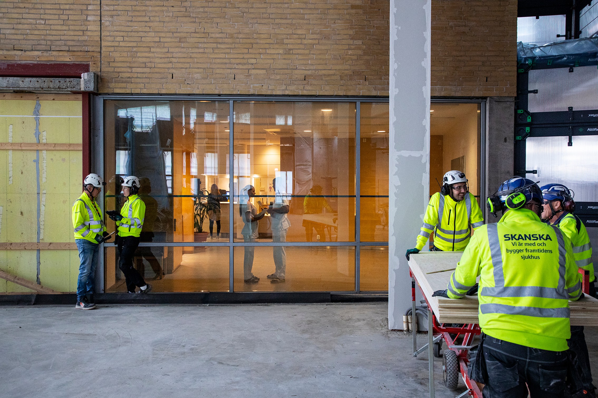 Byggnadsarbetare i högsynlighetsjackor inne i en byggnad under renovering.